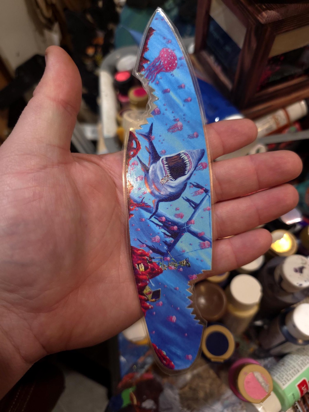 Long blue stained-glass-style blade-shaped print held in a hand